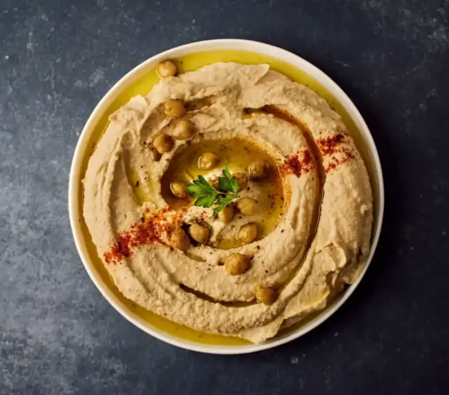 חומוס עבודת יד עם פול ושמן זית, מוגש בצלחת, מומלץ לטעום בחומוסייה בגליל.