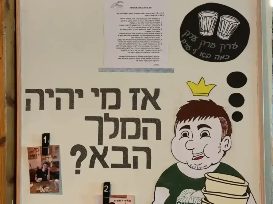 שלט עם דמות מצוירת, תמונות וכתוביות על חומוס הבוטקה והמסעדה.