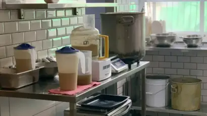 מטבח של חומוסייה עם מכשירים וסירים, משטח עבודה נקי ומסודר.