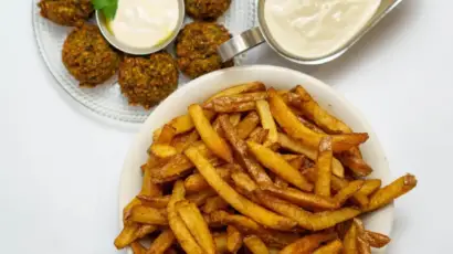צלחת עם פ fries חמות, קציצות ירק ורוטב סמיך, מצגת טעים מחומוסיה בגליל.