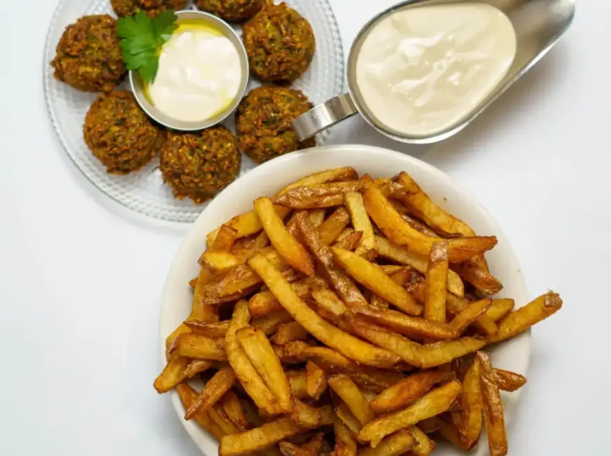 צלחת עם פ fries חמות, קציצות ירק ורוטב סמיך, מצגת טעים מחומוסיה בגליל.